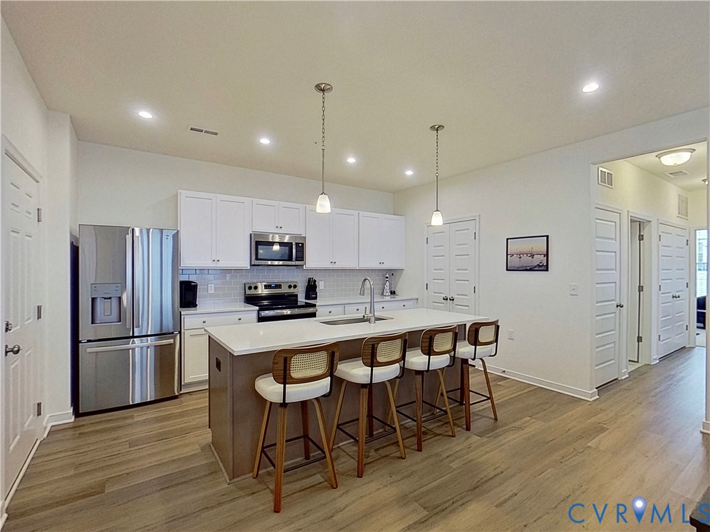 12423 Wescott Avenue Midlothian, VA 23112 - Photo 5 of 25 a kitchen with stainless steel appliances a refrigerator a stove a sink dining table and chairs with wooden floor