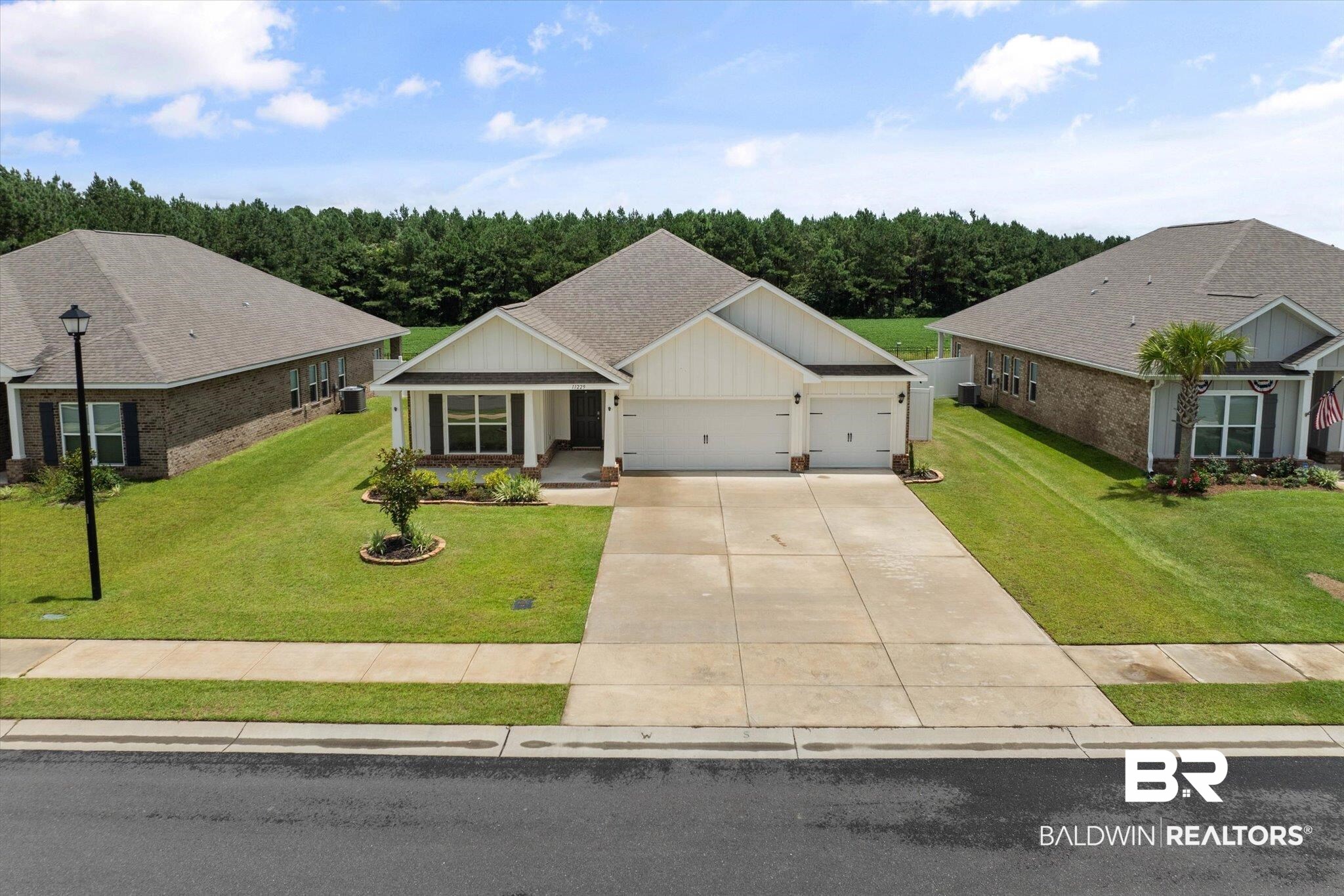 11229 Genuine Risk Circle Daphne, AL 36526 - Photo 31 of 46 View of front facade with concrete driveway, an attached garage, a front lawn, roof with shingles, and board and batten siding