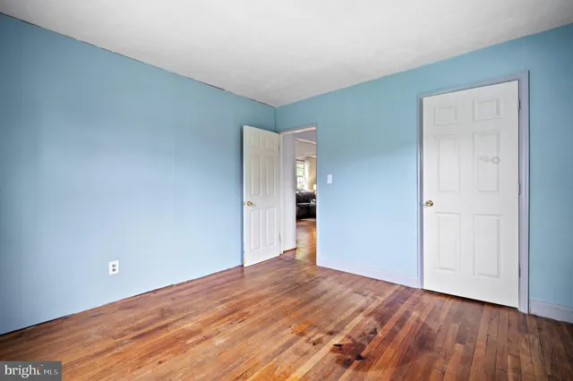 a view of an empty room with wooden floor and closet