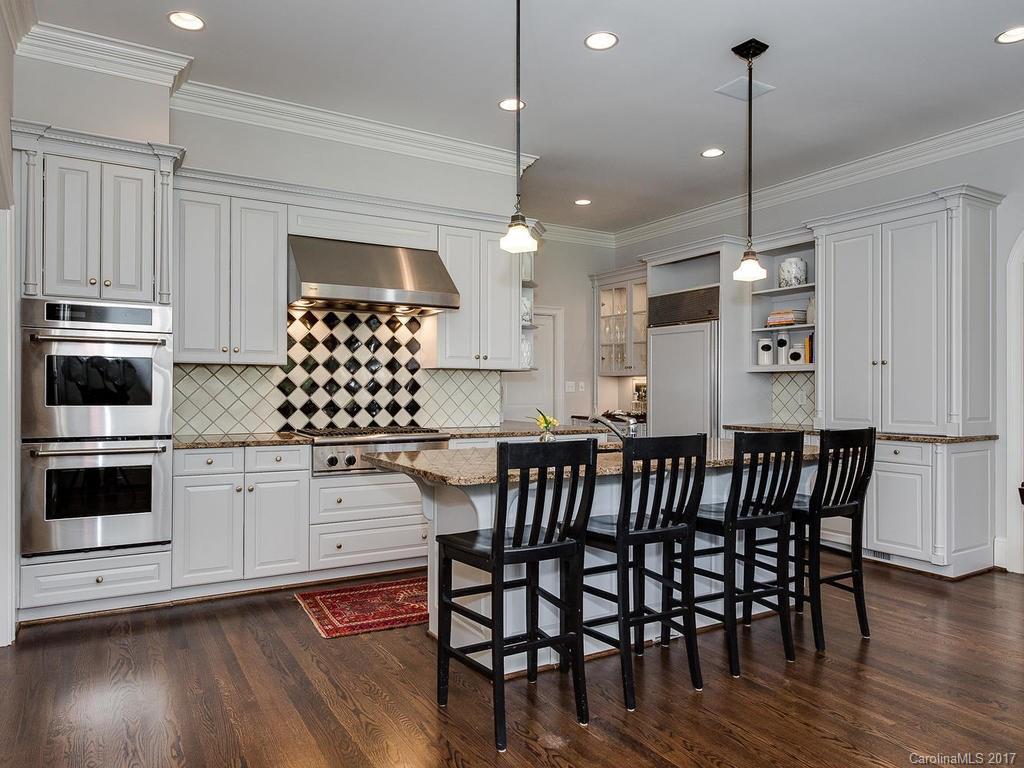 1900 Harris Road Charlotte, NC 28211 - Photo 6 of 24 a kitchen with stainless steel appliances granite countertop a stove a sink a microwave a dining table and chairs with wooden floor
