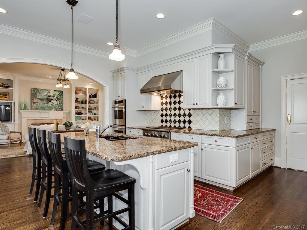 1900 Harris Road Charlotte, NC 28211 - Photo 7 of 24 a kitchen with stainless steel appliances granite countertop a stove a sink dishwasher a dining table and chairs with wooden floor