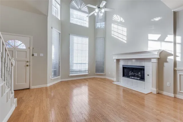 a view of an empty room with wooden floor fireplace and a window