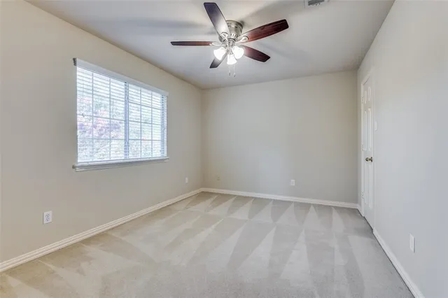 an empty room with windows and ceiling fan