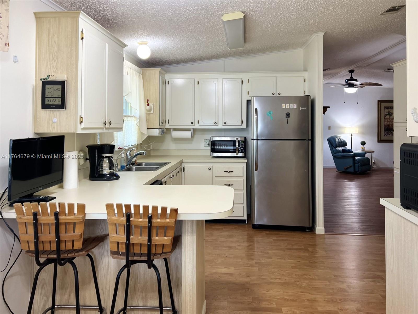 6367 Southwest 83rd Place Ocala, FL 34476 - Photo 26 of 47 a kitchen with stainless steel appliances a refrigerator a stove a sink a dining table and chairs with wooden floor