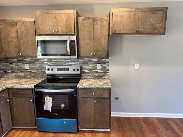 a kitchen with granite countertop a stove and a microwave