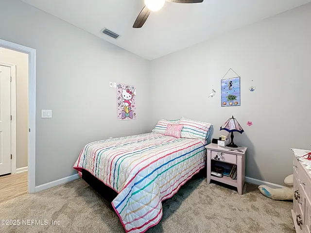 a living room with furniture a ceiling fan and a refrigerator