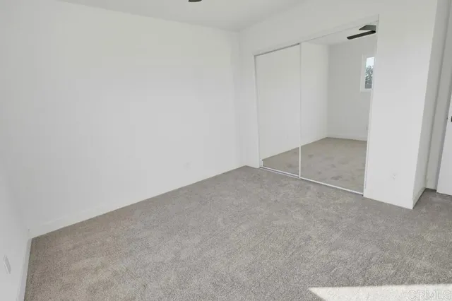 an empty room with a ceiling fan and window