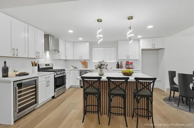 a kitchen that has a lot of cabinets in it with stainless steel appliances granite countertop a dining table and chairs a oven with wooden floors
