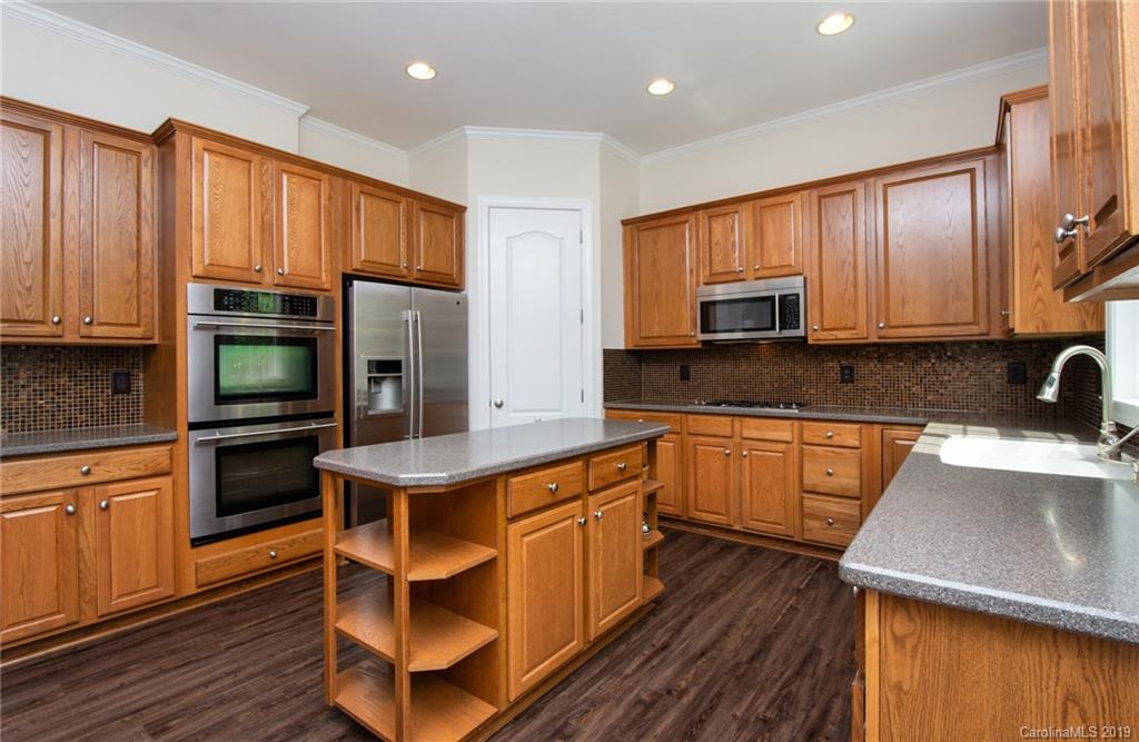 538 Quicksilver Trail Fort Mill, SC 29708 - Photo 11 of 39 a kitchen with stainless steel appliances wooden cabinets a stove a sink and a microwave