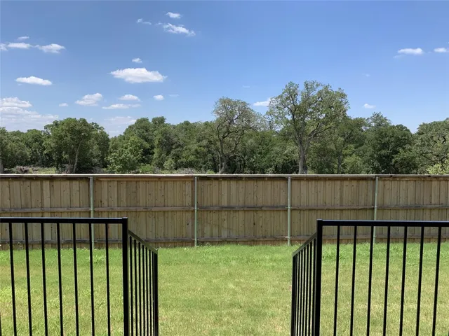a view of backyard with barbeque grill and wooden fence