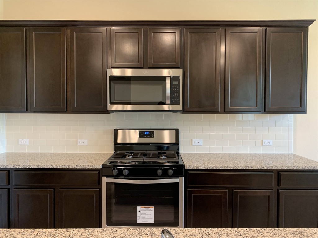 100 Royal Palm Way Leander, TX 78641 - Photo 6 of 29 a kitchen with granite countertop stainless steel appliances wooden cabinets and a stove top oven