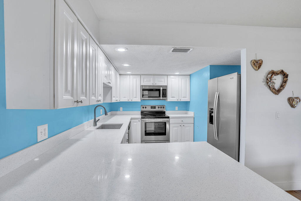 715 South Ocean Drive, Unit G Fort Pierce, FL 34949 - Photo 14 of 24 a kitchen with granite countertop a refrigerator and a stove top oven