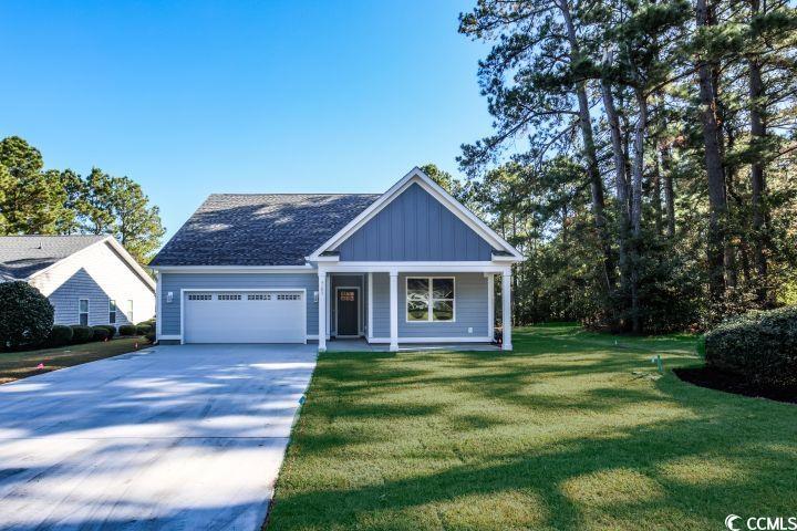 View of front of house featuring a porch, board and batten siding, concrete driveway, a front lawn, and a garage