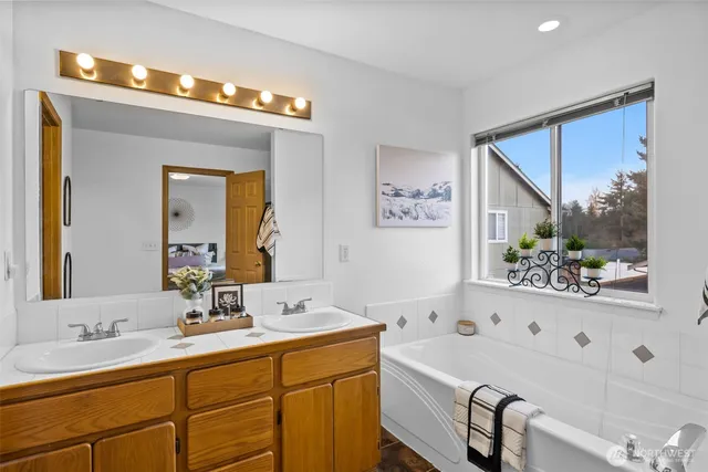 a bathroom with a tub a sink and mirror