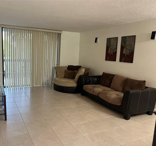 a living room with couches and kitchen view with wooden floor