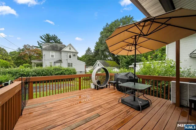 a view of a roof deck with table and chairs under an umbrella with wooden floor