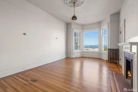 a view of an empty room with a window and wooden floor
