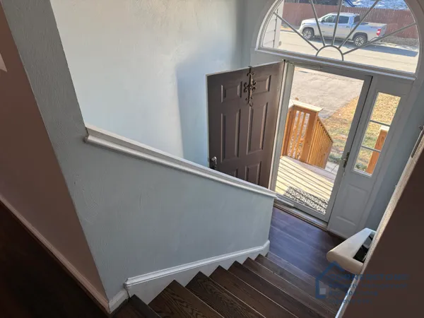 a view of a hallway with wooden floor and stairs