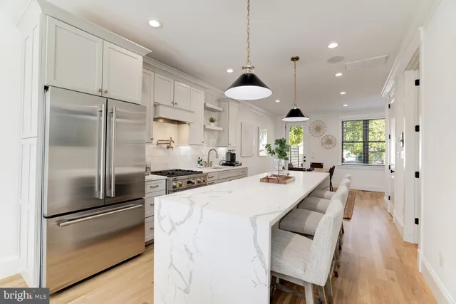 a kitchen with stainless steel appliances granite countertop a stove a sink a refrigerator a stove a dining table and chairs