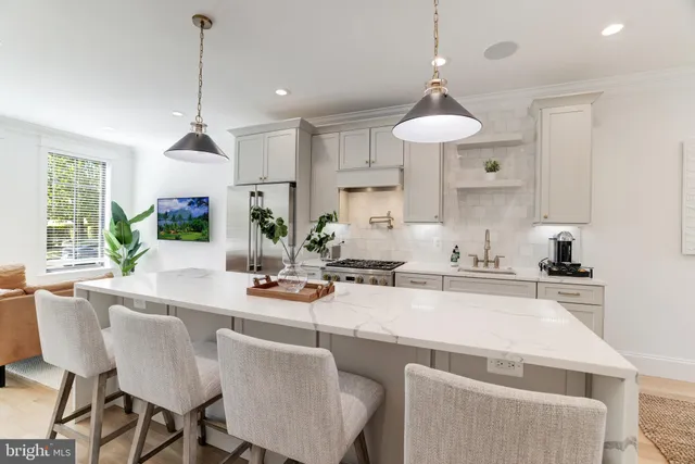 a kitchen with stainless steel appliances granite countertop a stove a sink a refrigerator a dining table chairs and white cabinets