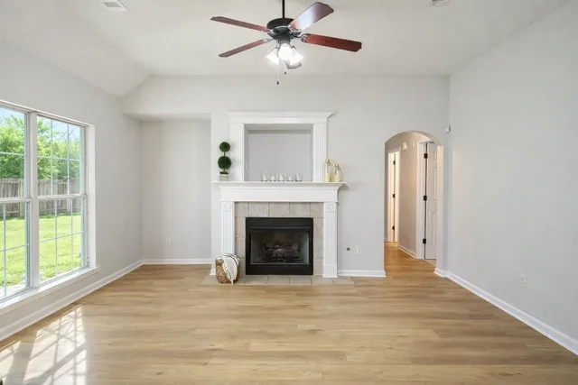 a view of a livingroom with a fireplace a ceiling fan and wooden floor
