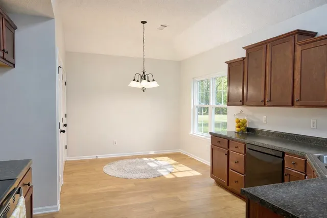 a kitchen with stainless steel appliances granite countertop a sink a stove and a wooden floors