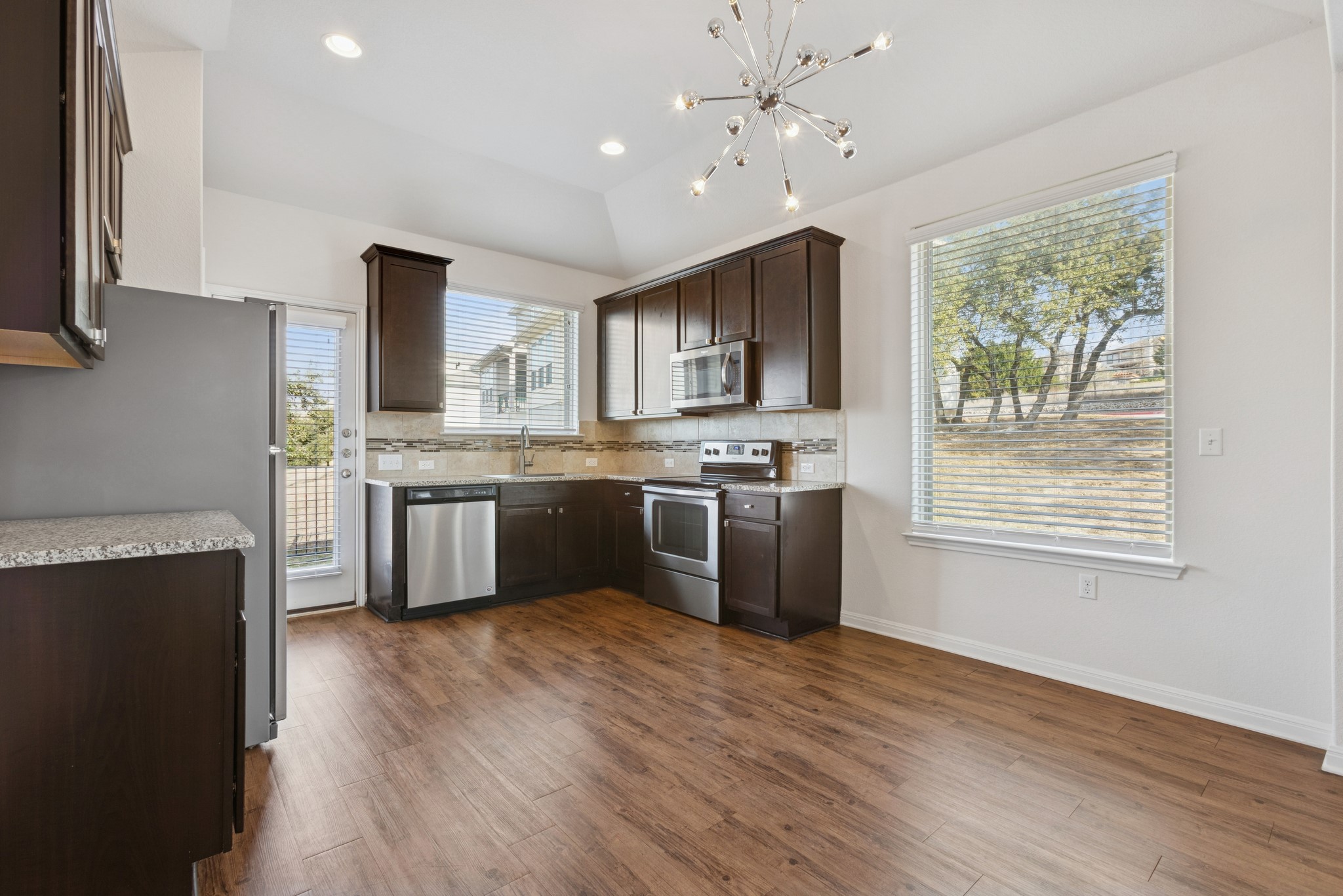 6104 Steep Cactus Trail Austin, TX 78735 - Photo 4 of 17 The kitchen features dark wood cabinetry, stainless steel appliances, granite countertops, and wood-style flooring