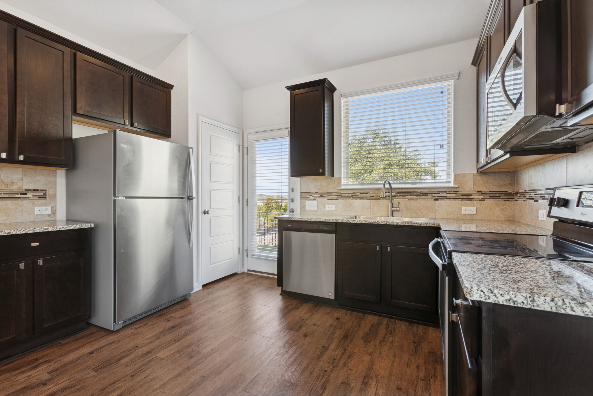 6104 Steep Cactus Trail Austin, TX 78735 - Photo 5 of 17 The kitchen features dark wood cabinetry, granite countertops, and stainless steel appliances