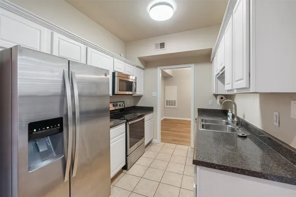 a kitchen with granite countertop a refrigerator and a sink
