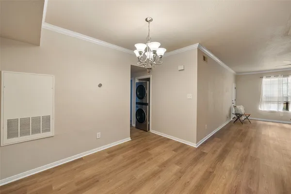 a view of a room with wooden floor chandelier and windows