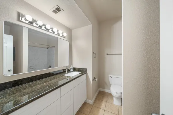 a bathroom with a granite countertop sink a toilet and a mirror