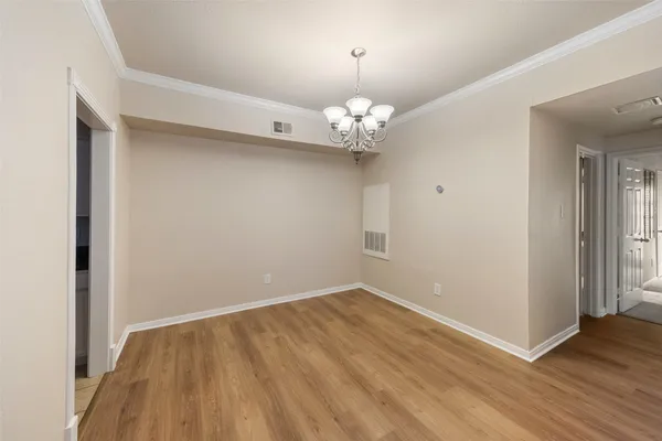 an empty room with wooden floor and chandelier