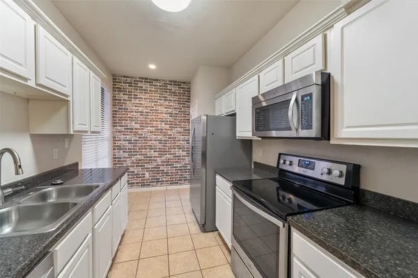 a kitchen that has a sink wooden cabinets and stainless steel appliances