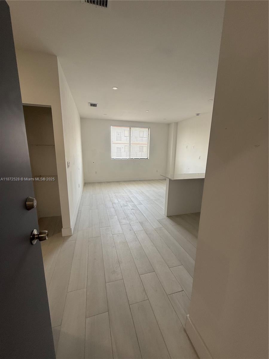 1091 East 17th Street, Unit 304 Hialeah, FL 33010 - Photo 2 of 25 wooden floor in an empty room with a window