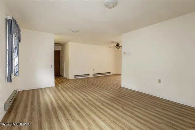 an empty room with wooden floor a ceiling fan and windows