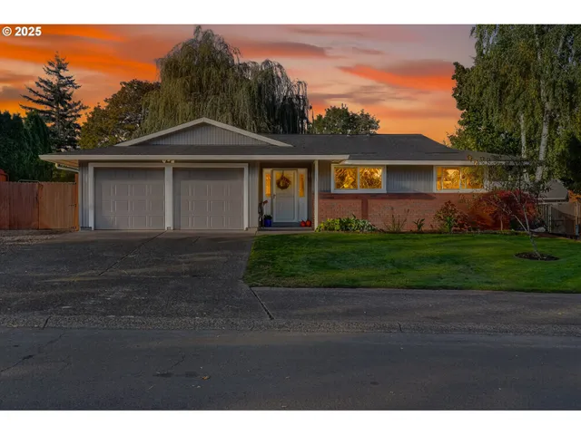 a view of a yard in front of a house with large windows