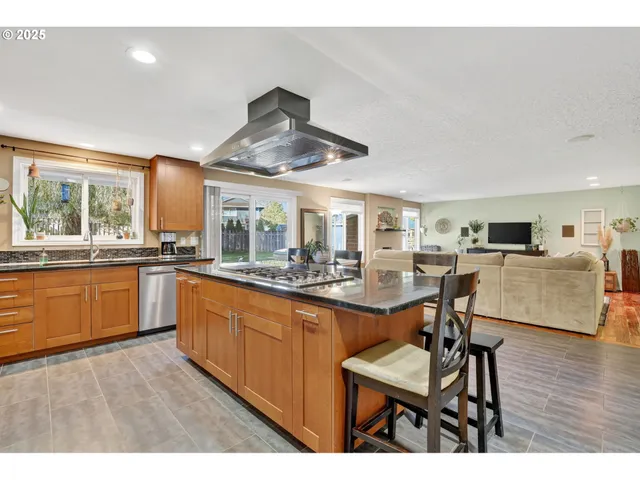 a kitchen with stainless steel appliances kitchen island granite countertop a table chairs and a refrigerator