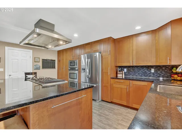 a kitchen with stainless steel appliances granite countertop a refrigerator a stove and a sink