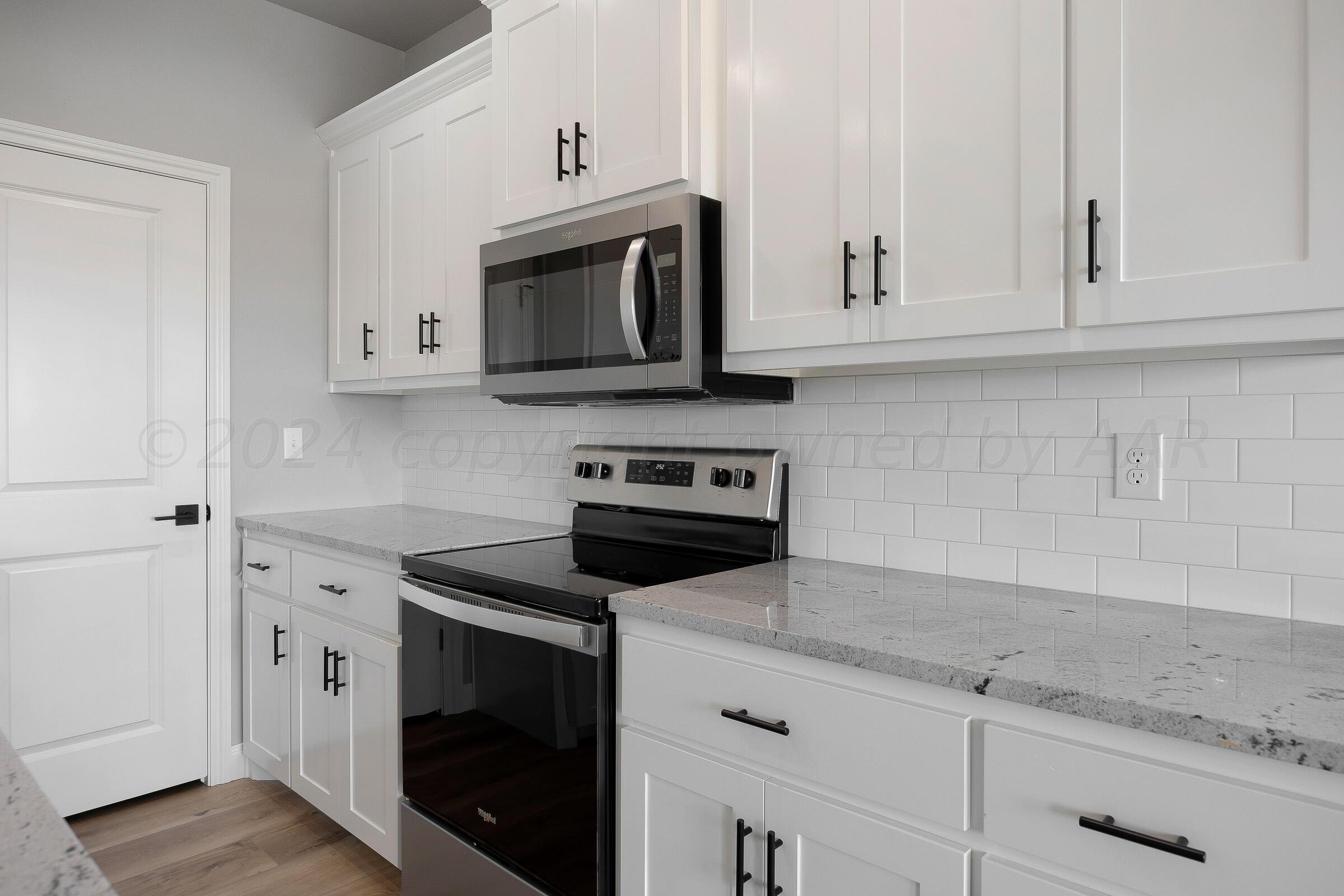 7501 John Thomas Street Amarillo, TX 79119 - Photo 10 of 30 a kitchen with white cabinets and black appliances