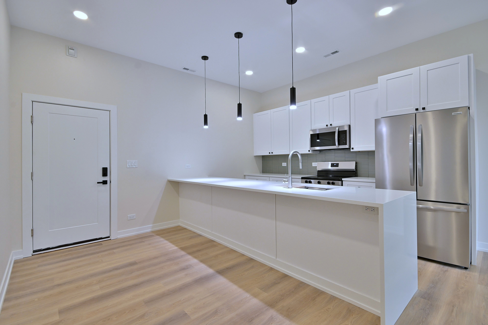 7518 Madison Street, Unit E Forest Park, IL 60130 - Photo 6 of 30 a kitchen with kitchen island white cabinets and stainless steel appliances