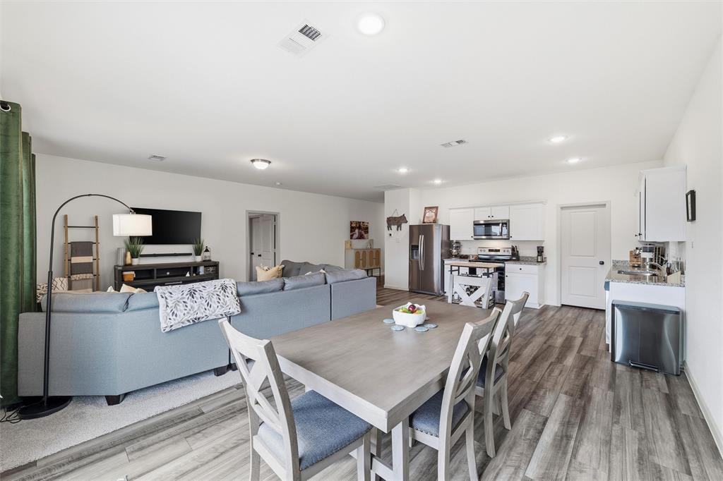 2616 Beech Crk Road Glenn Heights, TX 75154 - Photo 19 of 40 a kitchen with stainless steel appliances kitchen island granite countertop a sink a stove a microwave a dining table and chairs with wooden floor