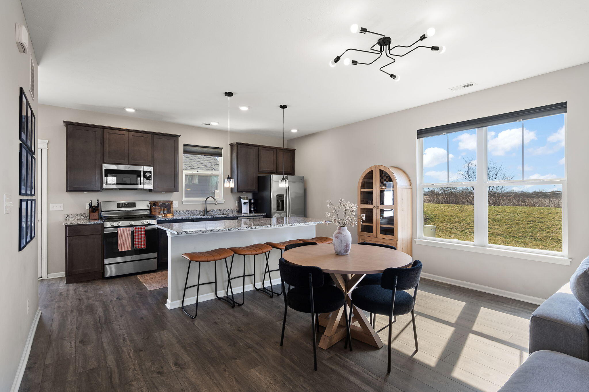 11897 Rhode Island Street Crown Point, IN 46307 - Photo 7 of 21 a kitchen with stainless steel appliances granite countertop a stove a refrigerator a sink a dining table and chairs with wooden floor