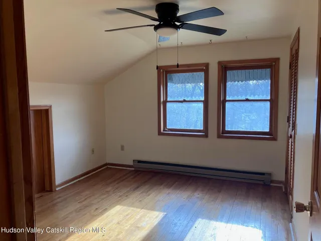 an empty room with wooden floor closet and windows