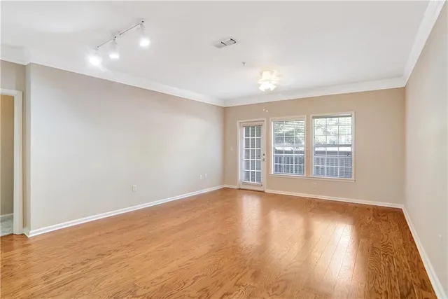 a view of an empty room with wooden floor and a window