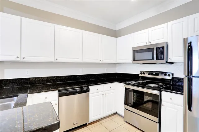 a kitchen with granite countertop white cabinets and black appliances