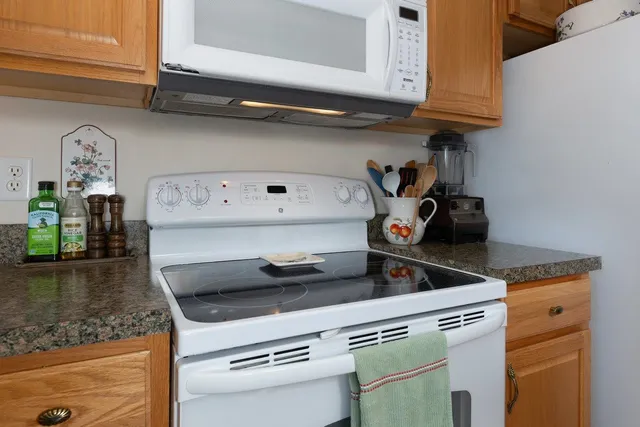 a living room with stainless steel appliances granite countertop furniture wooden floor and a view of bedroom