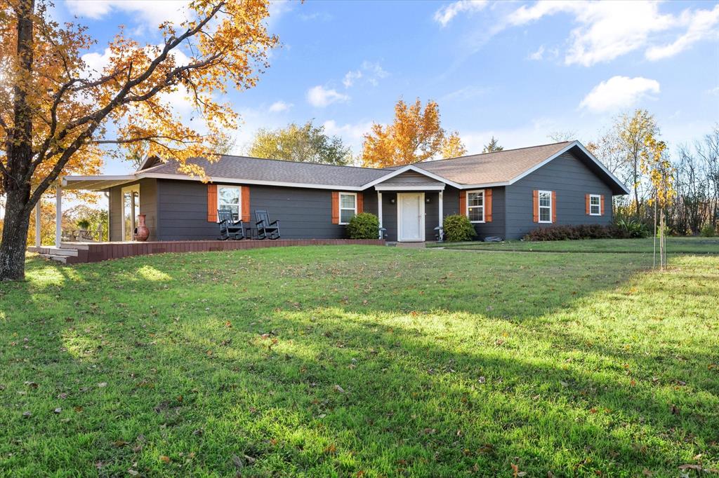 a view of a house with a big yard and large trees