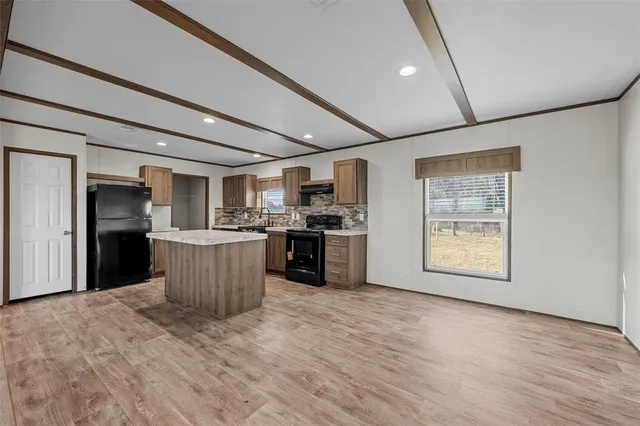 a kitchen with stainless steel appliances granite countertop a stove a sink a refrigerator white cabinets and wooden floor