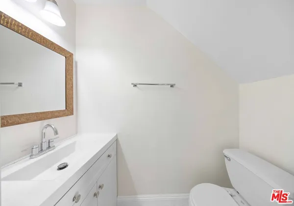 a bathroom with a toilet a sink a mirror and vanity