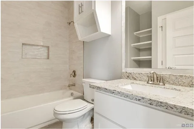 a bathroom with a granite countertop sink a toilet and bathtub
